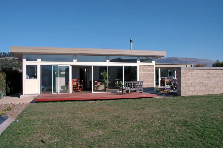 Earth House — exterior of the rammed-earth home with clerestory roof and deck