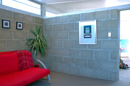 Earth House — living room with exposed block wall and red sofa