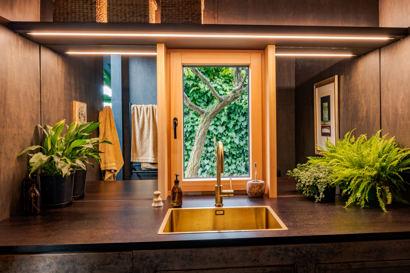 Garden House — bathroom with brass sink and window over a leafy outlook