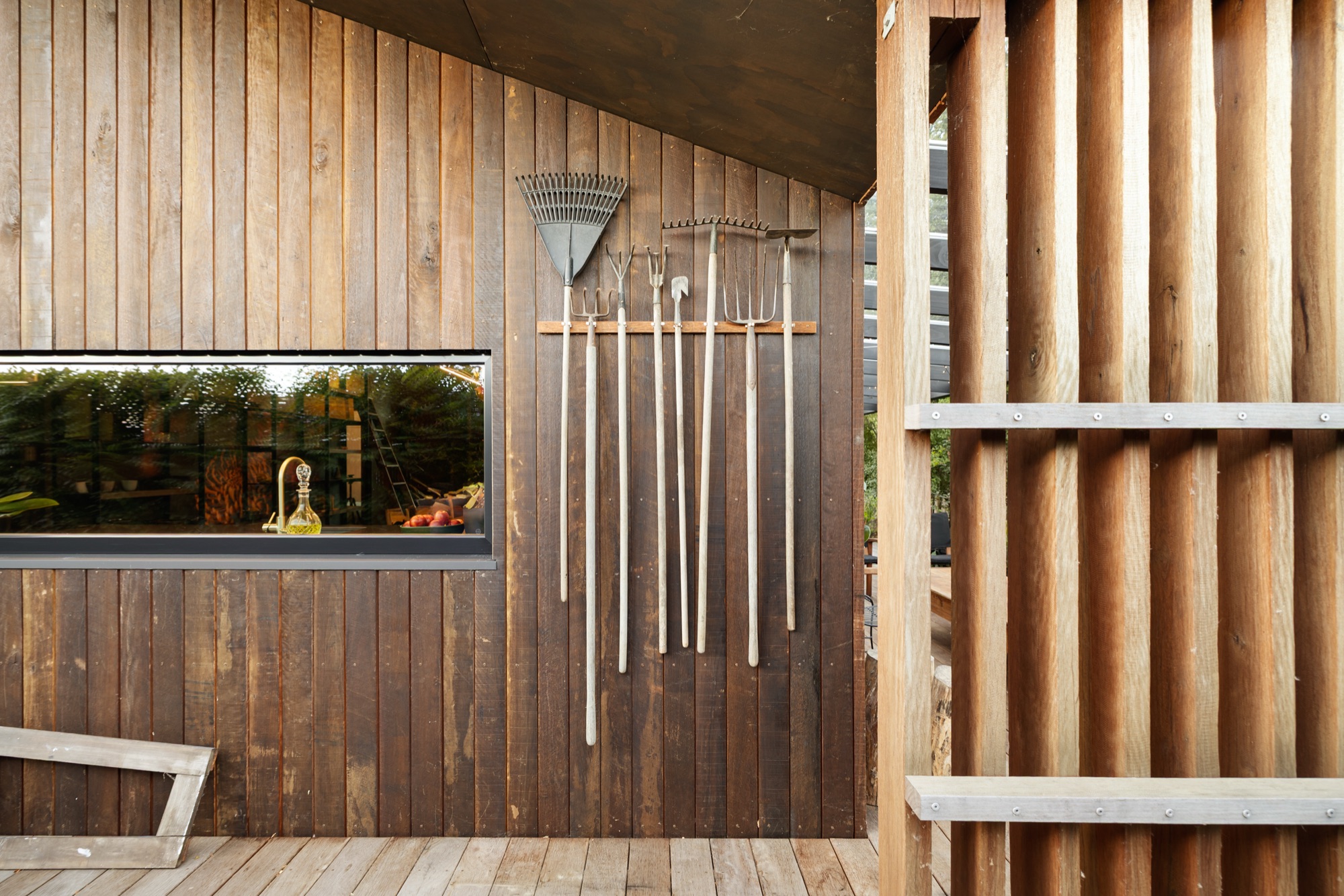 Garden House — cedar-clad exterior with garden tools beside the long kitchen window